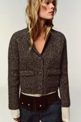 Chaqueta de punto con textura jaspeada, cuello solapa y manga larga. Presenta bolsillos delanteros de plastrón con solapa y cierre frontal con botones forrados a tono.