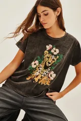 Remera de algodón con efecto lavado, cuello redondo y mangas cortas. Presenta un estampado frontal con un guepardo rodeado de flores y la palabra 'SAVAGE' en letras doradas.