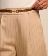 Bermuda sastrera color beige con estampa de raya de tiza, corte alargado, cinturón fino en la cintura y pliegues.