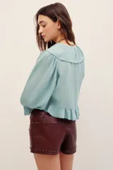 Camisa crop de viscosa color verde menta, con escote en V pronunciado, volados en el cuello y el frente, y mangas tres cuartos con puños elastizados.