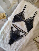 Conjunto de lencería de encaje negro compuesto por un bralette con detalle de aro central y una tanga de doble tira regulable estilo less.