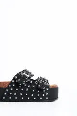 Sandalia plataforma de diseño estilo Birkenstock en color negro, con dos tiras ajustables con hebillas metálicas, decoradas con múltiples tachas y ojales plateados.