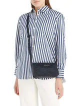 Cartera tipo bandolera de Tommy Hilfiger, confeccionada en poliuretano con patrón jacquard de monogramas en tonos azul marino. Presenta cierre superior con cremallera y detalles distintivos de la marca en los laterales.