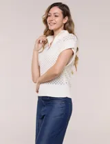Buzo de punto color marfil, confeccionado en algodón calado con cuello alto acanalado y medio cierre metálico dorado. Presenta mangas cortas estilo japonesa con puños anchos y un zócalo acanalado en el ruedo.