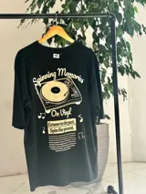 Remera oversize blanca de manga corta, con gran estampado en la espalda de una bandeja de vinilos y texto temático musical.