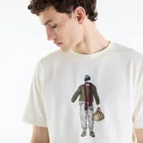 Remera de manga corta New Balance Varsity para hombre, de color blanco marfil con calce relajado y cuello redondo. Presenta un estampado gráfico central con diseño ilustrado y texto bordado en el borde inferior.