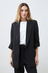 Blazer de corte recto y diseño minimalista, con solapas clásicas, bolsillos laterales con solapa y mangas tres cuartos con detalle de botón.