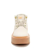 Bota tipo chukka Caterpillar con plataforma dentada de goma en color caramelo. El cuerpo de la bota es de color beige claro, con cordones al tono, ojales metálicos dorados y el logo de la marca grabado en el lateral y la lengüeta.