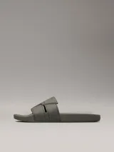 Ojotas tipo slide de color verde oliva, con doble tira superior de TPU con relieve y logotipo grabado. Cuentan con plantilla moldeada ergonómica con soporte para el arco plantar y suela de EVA.