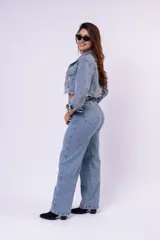 Campera de jean cropped con tachas plateadas distribuidas en el frente, hombros y mangas. Presenta un diseño con bordes deshilachados, cuello clásico y cierre frontal con botones metálicos.