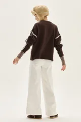 Sweater de tejido de punto color beige, con cuello redondo y detalles de bordado en zigzag en color azul oscuro a lo largo de las mangas y hombros. Presenta un pequeño bordado con texto en el pecho.