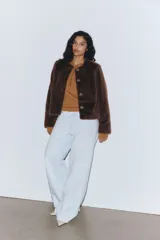 Campera de textura suave efecto peluche, color marrón, con cuello redondo, cierre frontal con botones y forro interior.