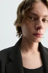 Blazer azul marino de corte recto, confeccionada en tejido con viscosa. Tiene cuello con solapas de muesca, manga larga con puño abotonado, bolsillo de vivo en el pecho y bolsillos de parche en la cadera. El bajo tiene aberturas en la espalda y el cierre es con botonadura frontal.