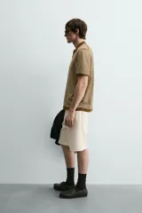 Polo de punto de algodón con corte regular fit, manga corta y cuello solapa con abertura frontal en forma de V. Presenta un diseño a rayas horizontales marrones y beige, con ribetes en color marrón oscuro en el cuello, puños y bajo.