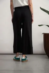 Pantalón negro de corte recto y tiro alto, con cintura elástica y lazo ajustable del mismo tejido. Presenta bolsillos laterales y un dobladillo ancho en la parte inferior.