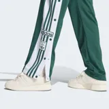 Pantalón deportivo Adidas Adibreak de corte holgado, color verde con franjas laterales blancas y las icónicas tres rayas en verde. Presenta botones a presión a lo largo de los laterales y logo de la marca en la parte inferior.