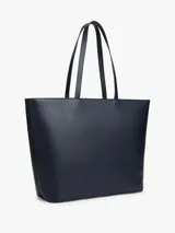 Cartera tipo tote de Tommy Hilfiger en color azul marino, con diseño de franjas verticales en el centro en tonos blanco, azul y rojo. Presenta logo metalizado dorado en la parte frontal y doble asa superior.
