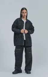 Campera negra de tejido liviano, con cuello camisero, cierre frontal de broches y puños elásticos. Posee múltiples bolsillos frontales con solapa y detalles reflectantes en blanco.