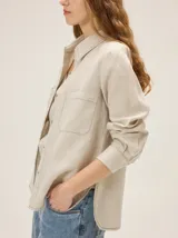 Camisa de lino color crudo con bolsillos frontales con solapa, cuello camisero, mangas largas y pespuntes en contraste.