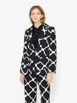 Blazer negro con estampado geométrico blanco, cuello con solapa, acceso con broche y bolsillos plaque.