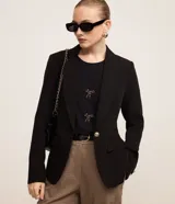 Blazer negro de crepé con cuello solapa, manga larga, bolsillos con solapa y cierre de un solo botón dorado.