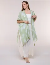 Kimono de gasa verde con estampado de hojas blancas y detalles de lurex. Presenta mangas cortas holgadas, diseño abierto al frente y terminación en punta con borlas en el ruedo.