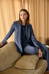 Blazer de terciopelo azul con solapas anchas y cierre frontal de un botón. Presenta un diseño entallado de manga larga con textura suave y acabado ligeramente brillante.