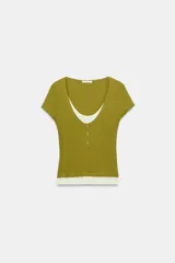 Camiseta efecto doble en color crudo y blanco, de manga corta y corte slim fit. Cuenta con escote redondo, cierre frontal parcial con botones a presión y diseño de capas superpuestas.
