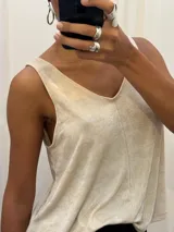 Musculosa de corte holgado y diseño acampanado, con escote en V y breteles anchos. Presenta un acabado con sutil brillo dorado sobre una base de color beige.