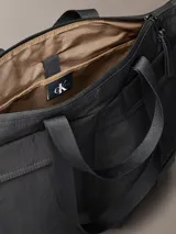 Bolso tote Calvin Klein negro de nailon reciclado, con cierre de cremallera, doble asa de mano y dos bolsillos externos con cremallera.