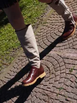 Botas altas de cuero marrón combinadas con gamuza blanca con estampado de vaca, forradas en cuero y con cierre de bronce.