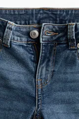 Jean de denim elástico color azul con efecto deslavado, tiro bajo, corte ajustado hasta la rodilla y diseño acampanado. Cuenta con cierre de botón y cremallera, bolsillos delanteros y bolsillos traseros con solapa y botón.