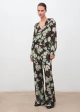 Blusa de gasa con estampado floral en tonos verdes y marrones, cuello escotado con cierre de lazo y mangas largas con puños abotonados.