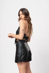 Short negro de tiro alto confeccionado en gabardina stretch metalizada, con bolsillos laterales y cierre frontal con cremallera y botón.