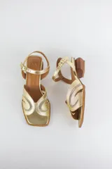 Sandalias doradas con capellada de cuero metalizado y malla, puntera cuadrada, tira ajustable al tobillo y taco geométrico de madera.