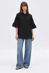 Camisa de algodón negra con cuello camisero, cierre frontal con botones y mangas 3/4 terminadas en volados.