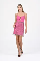 Vestido corto fucsia con breteles finos, escote con abertura y falda con flecos plateados.