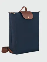 Mochila de diseño minimalista en color beige, con solapa y asa superior en cuero marrón texturizado. Cuenta con correas ajustables en color marrón y cierre principal.