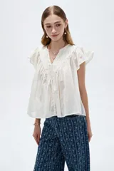 Blusa de algodón blanca con cuello en V, frunces frontales y mangas cortas con volados.