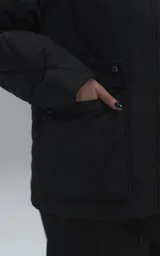 Campera oversize de microfibra opaca con diseño matelaseado de rombos. Presenta cuello de corderoy a tono, cierre frontal metálico y dos amplios bolsillos delanteros con solapa y broche snap. Interior forrado y relleno con guata térmica.