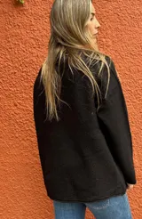 Saco de paño azul marino con solapas amplias y puños en corderito sintético color crema. Presenta detalles en cuero sintético marrón en la parte frontal y en las mangas, con un diseño abierto y corte recto.