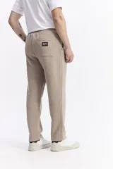 Pantalón de jogging color beige, confeccionado en algodón y poliéster, con cintura elástica y cordón ajustable. Diseño clásico sin puño en los tobillos.
