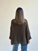 Sweater de punto abierto color marrón oscuro, de corte holgado, mangas largas y escote redondo.