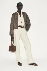 Chaqueta bomber color marrón con cuello redondo, manga larga con puño elástico y cierre frontal de cremallera metálica. Presenta un diseño de bordados florales en relieve por toda la prenda y bolsillos delanteros de vivo.