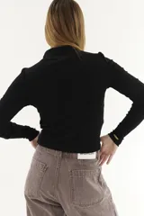 Polera blanca de algodón con cuello alto cruzado y mangas largas.