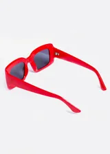 Lentes de sol rectangulares con armazón de plástico rojo y lentes oscuros.
