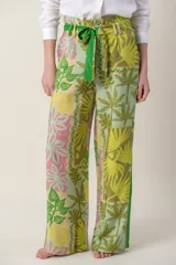 Pantalón ancho de tela blanca con estampado de flores azules, cintura alta con cordón ajustable y bolsillos laterales.