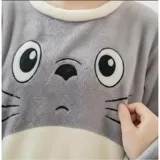 Conjunto de pijama de dos piezas confeccionado en tela de plush suave y abrigada. Incluye una remera de manga larga con diseño estampado de Totoro y pantalón largo a juego con puños en contraste.