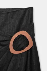 Falda midi negra de tiro alto con detalle de aplicación de madera a contraste en delantero y frunces. Cierre en espalda con cremallera oculta en costura.