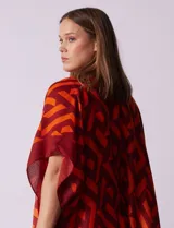 Kimono ligero de poliéster con estampado geométrico en tonos rojo oscuro y naranja. Presenta mangas anchas y terminación con borlas en los ruedos.